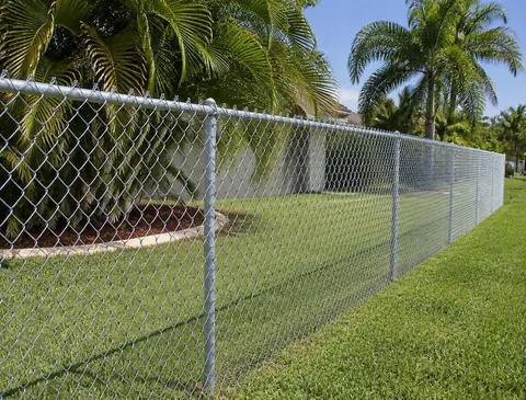 Galvanized chain link fence along a grassy backyard