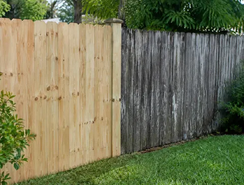 Wood fence with a section of new boards next to older weathered boards